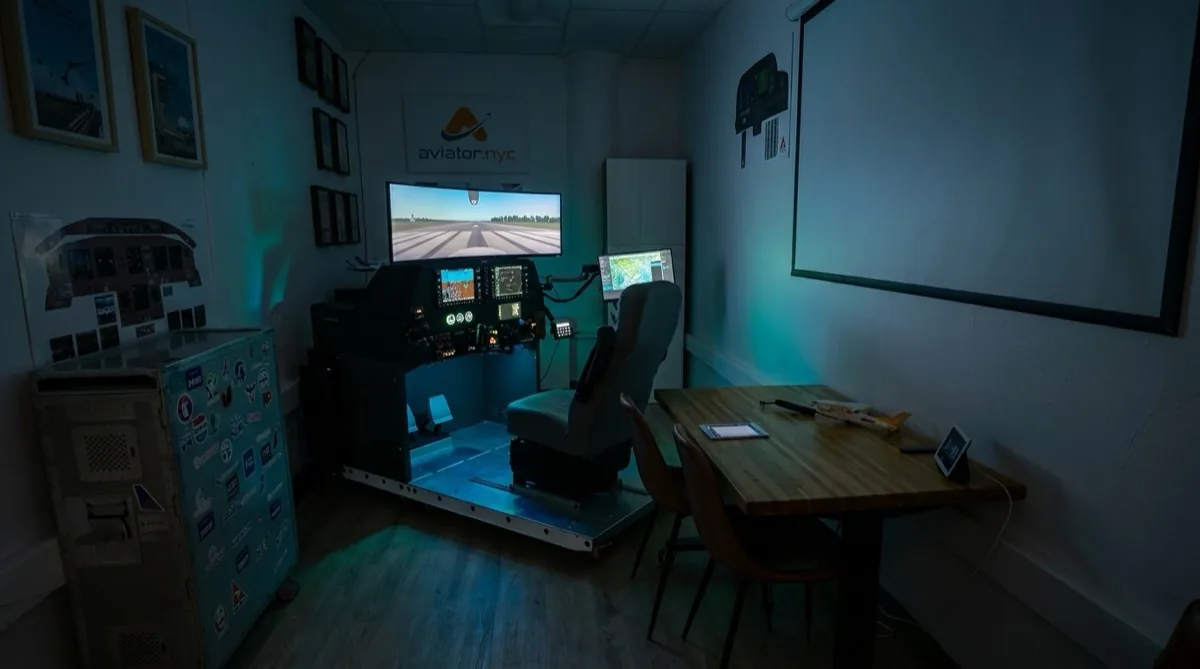 Aviator.NYC flight simulator training room at 131 Varick Street — PFC GTX G1000 NXi AATD with evening session lighting in Hudson Square, Manhattan