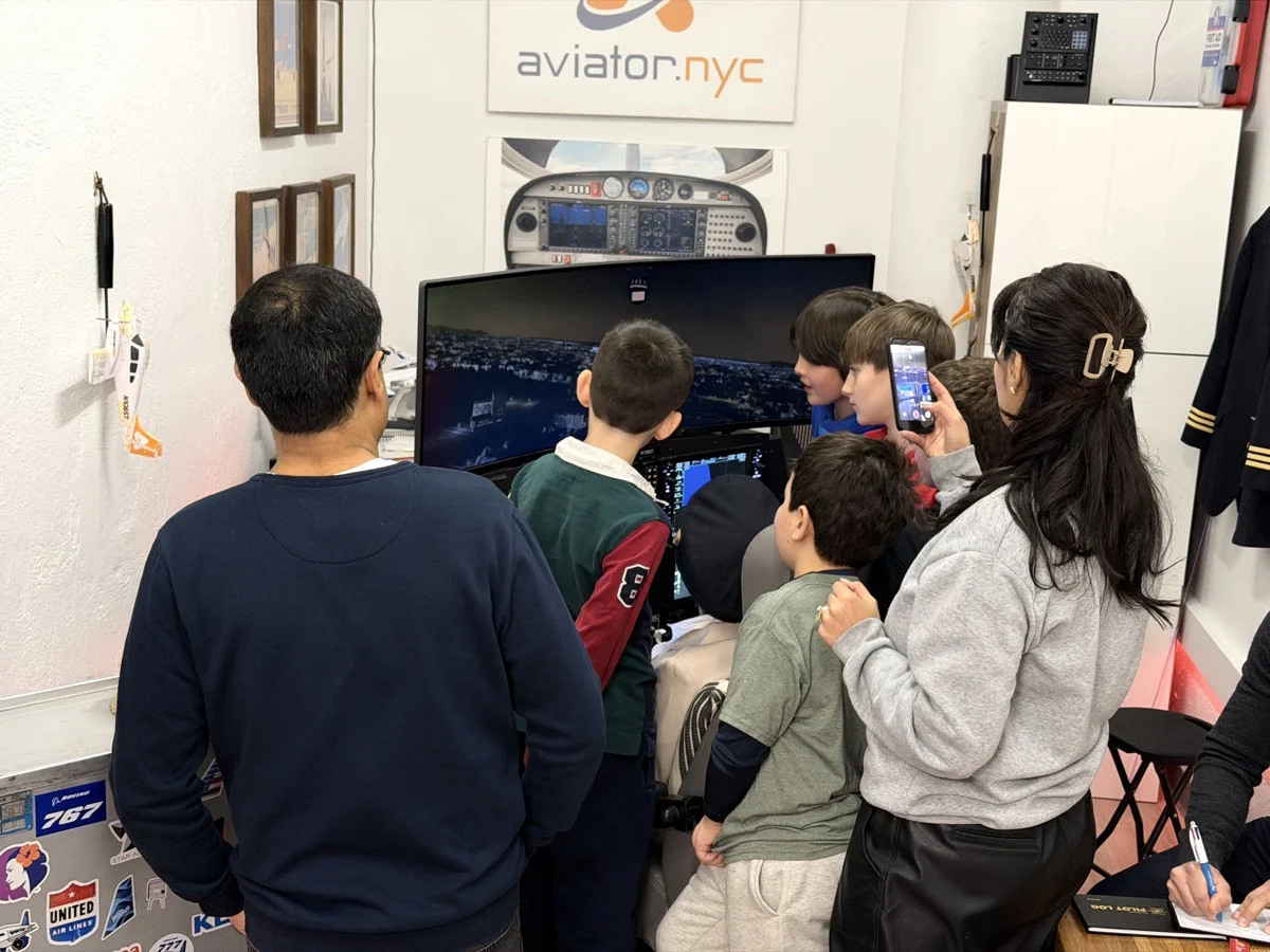 Kids gathered around flight simulator at Aviator.NYC birthday party in Manhattan