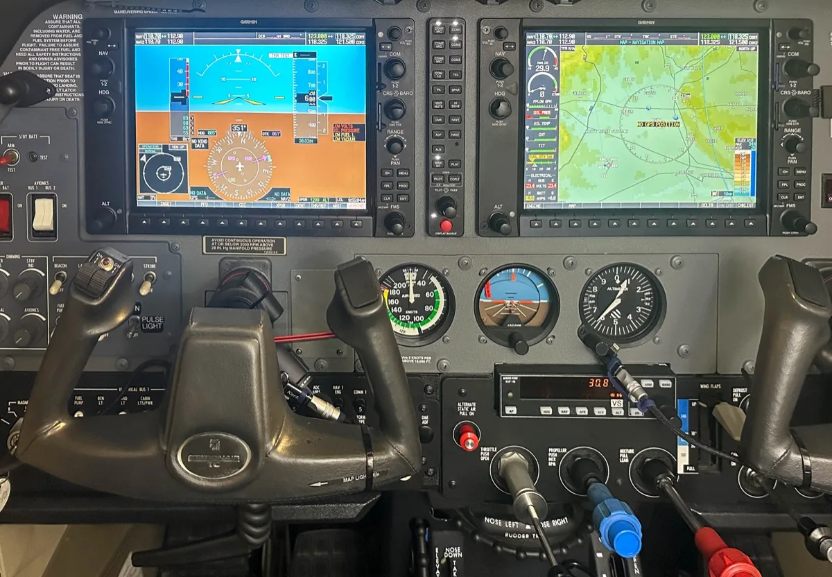 Garmin G1000 panel in a Cessna showing PFD and MFD with softkeys along the bottom of each display and standby analog instruments