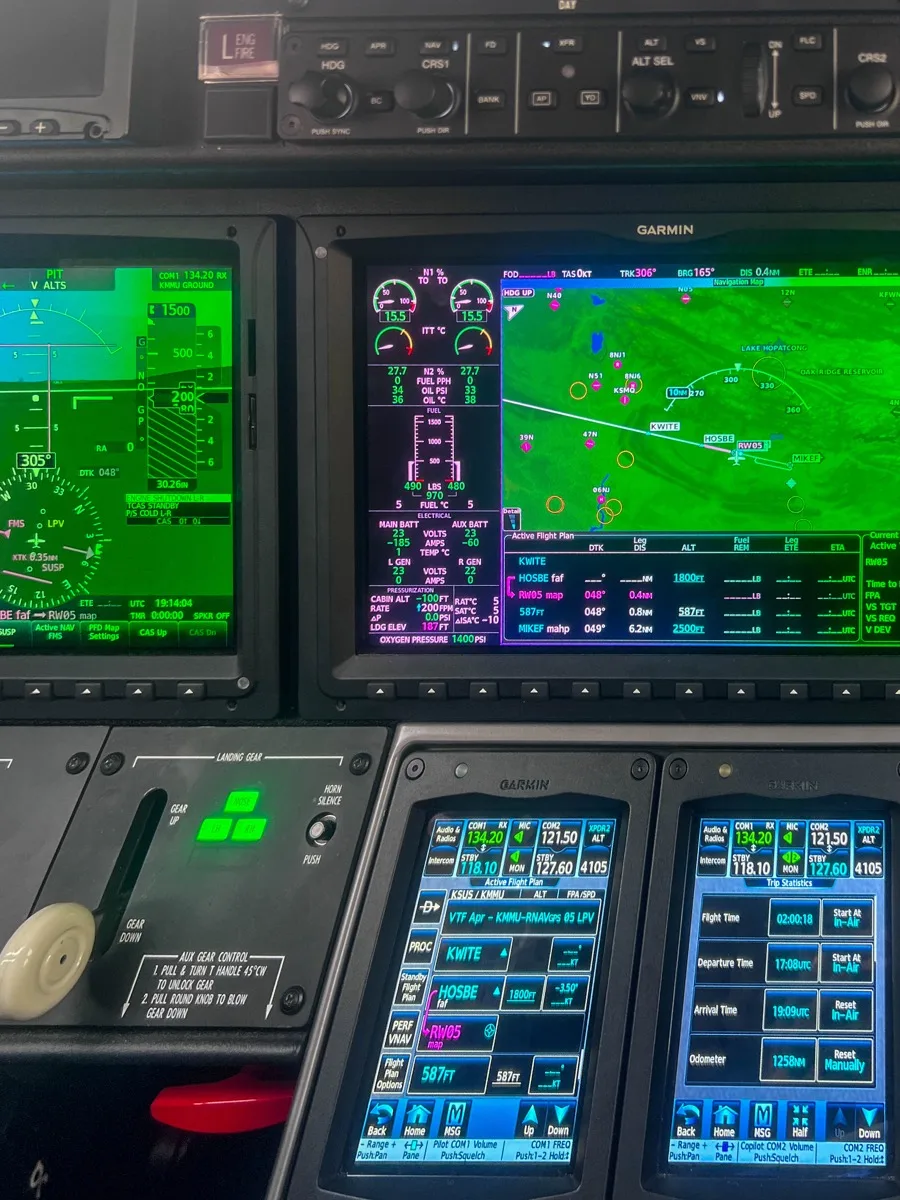 Garmin G3000 flight deck showing engine indications and navigation map on the main displays with two GTC touchscreen controllers below