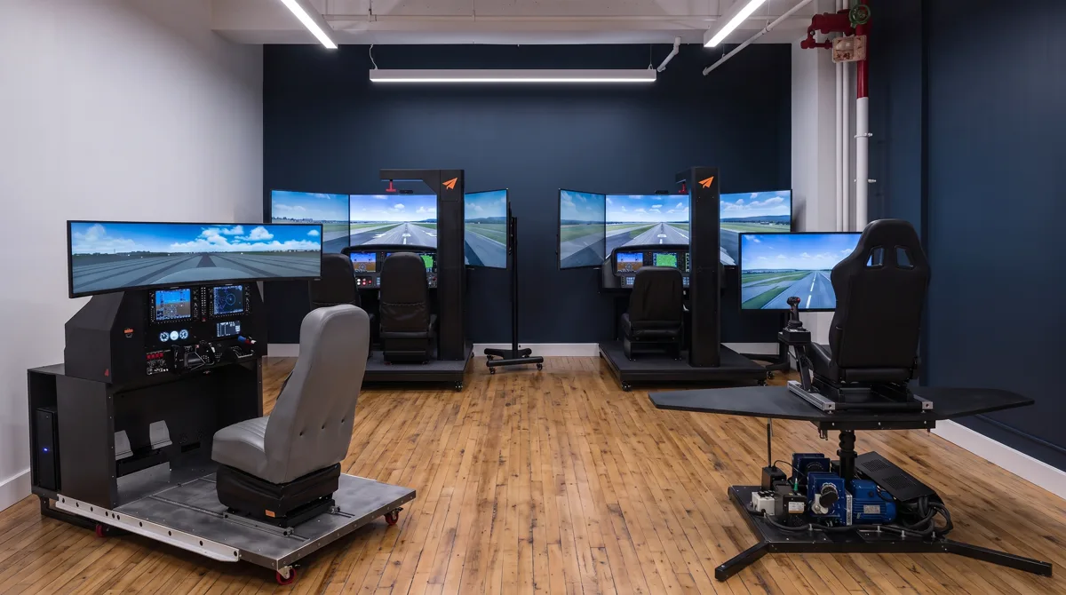 Rendering of the planned Midtown simulator bay seen from the entry: the G1000 simulator and a virtual reality motion simulator in front, and the two Cirrus simulators against the navy back wall